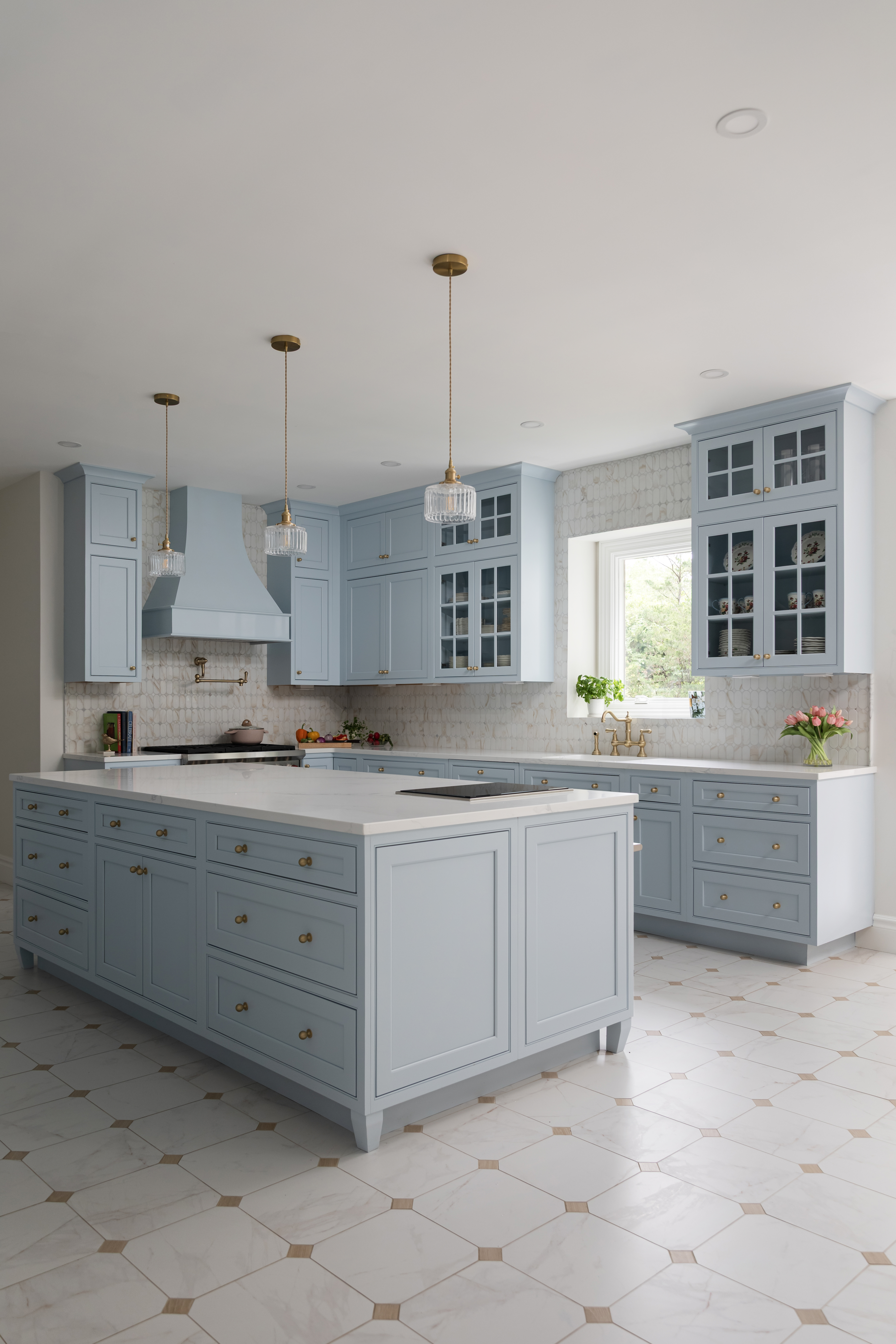 Long view of the kitchen showing the full island, hood wall, and window with tulips