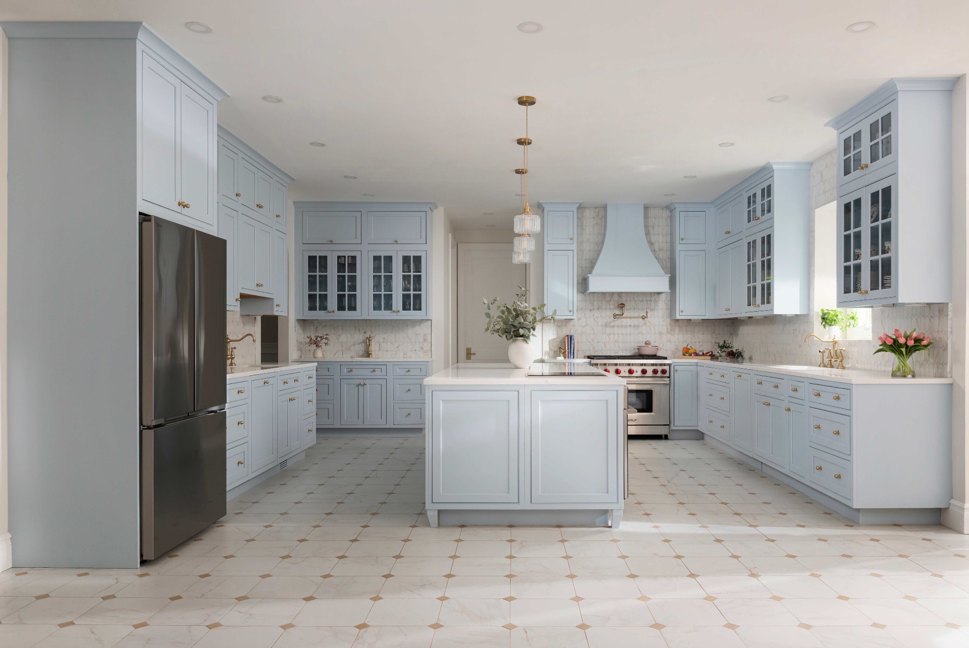 Wide view of the Moonmist blue kitchen with central island and arched range hood